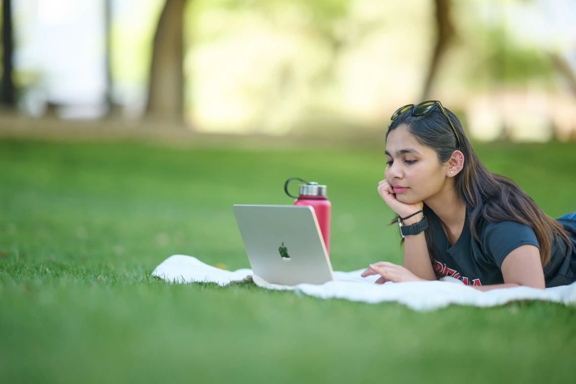 Student studying on grass lawn