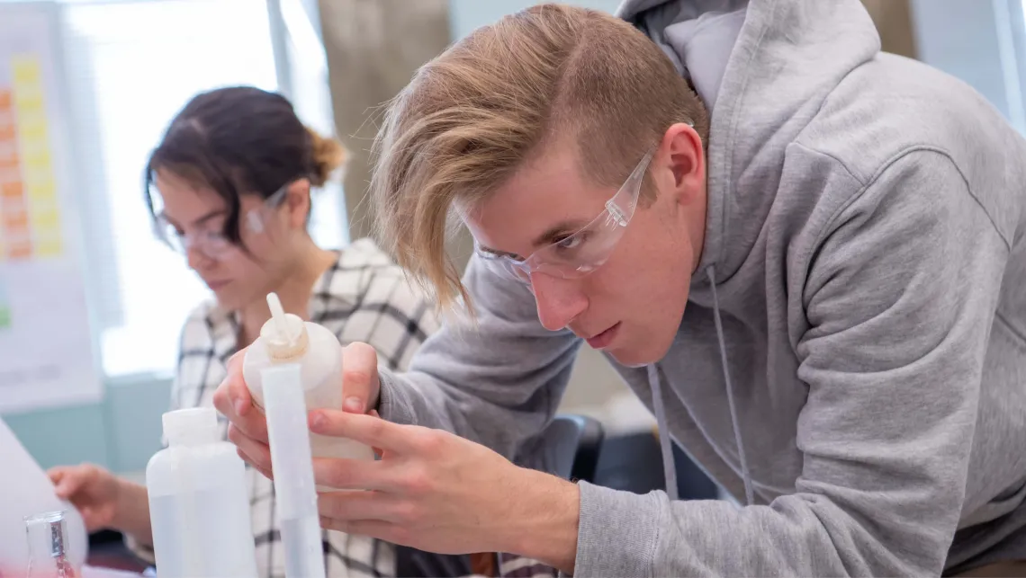 Student carefully measures how much of a solution to add to their experiment in a lab setting