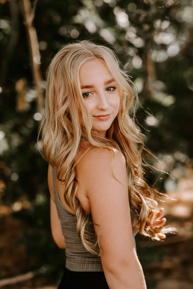 girl looking over shoulder with green tree background