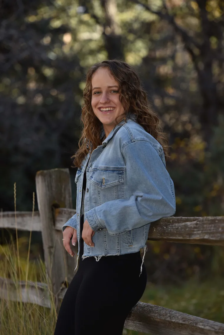 person leaning against fence wearing jean jacket