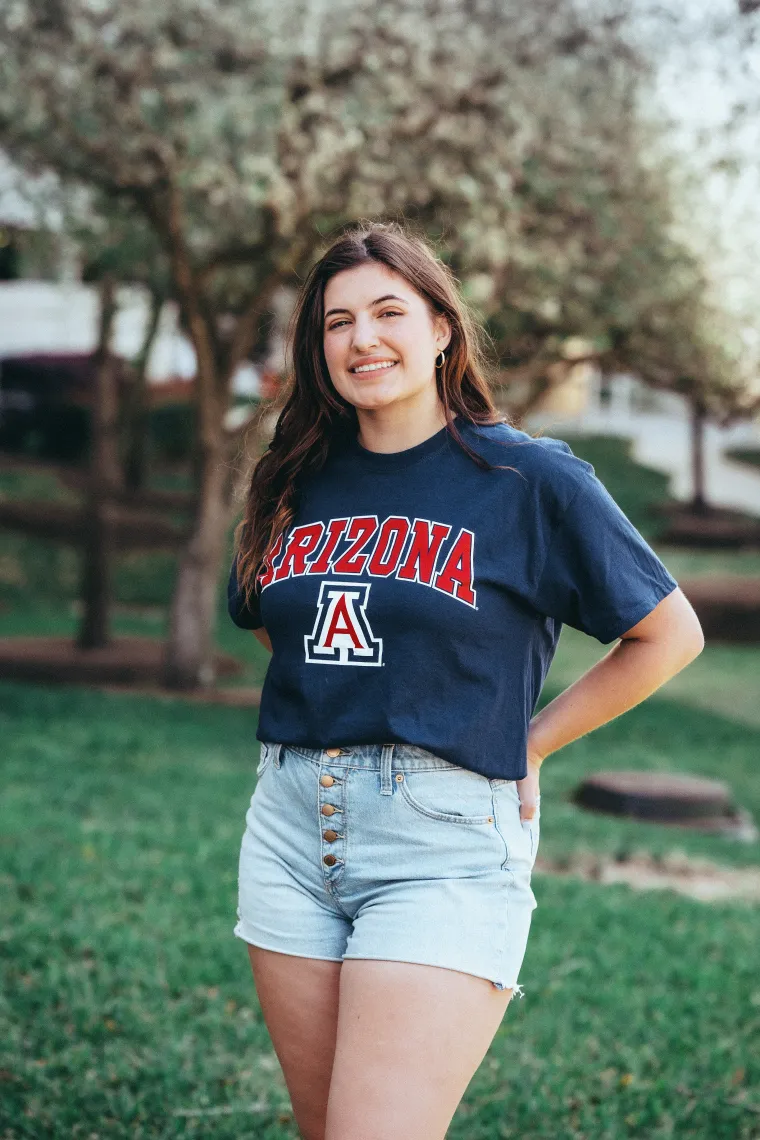 woman wearing blue university of arizona shirt standing in front of trees