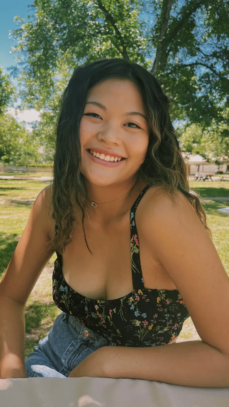 student sitting in front of green grass and trees