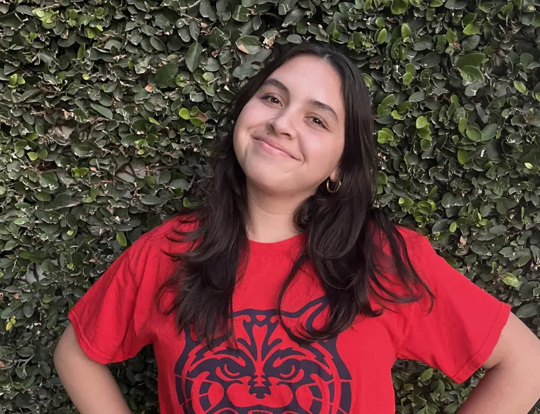 woman wearing red wildcat shirt standing in front of green leaf background