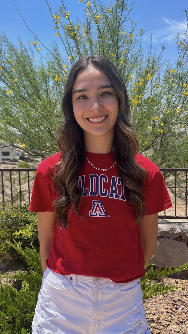 woman wearing red arizona shirt standing in front of green tree background