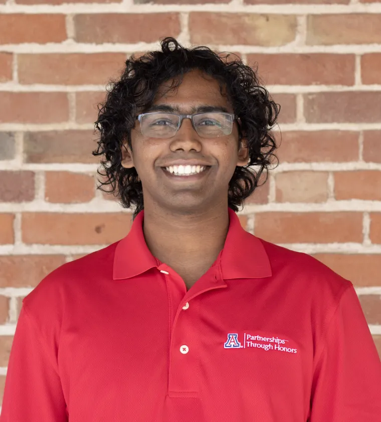 headshot of person wearing red shirt with brick background