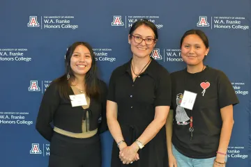 shelly lowe pictured alongside two students blue background