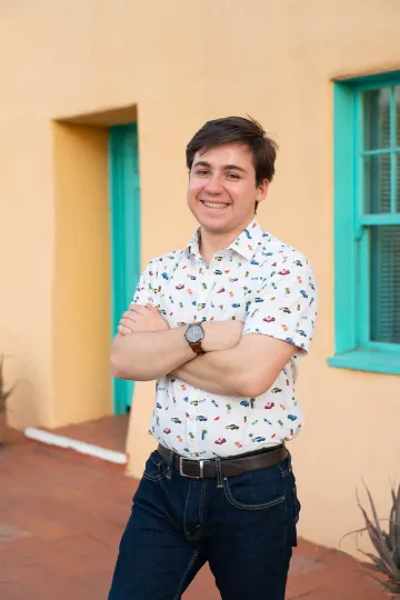 person wearing white shirt in front of yellow background, blue window frames