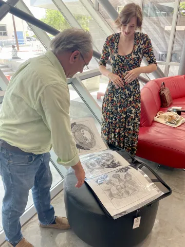 Patrick Baliani looking at Rachels sketchbook while she watches window background 