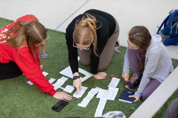 students working together looking at papers together on grass lawn