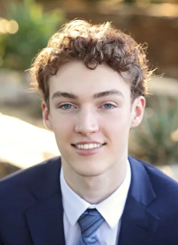 headshot of student with greenery background