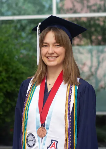 graduate in blue regalia and white stole wearing medallion