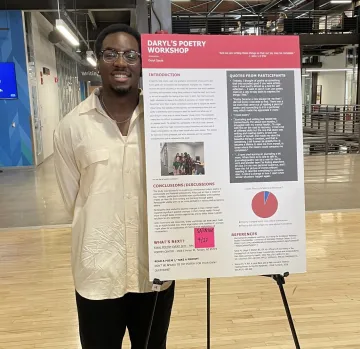 student standing next to poster