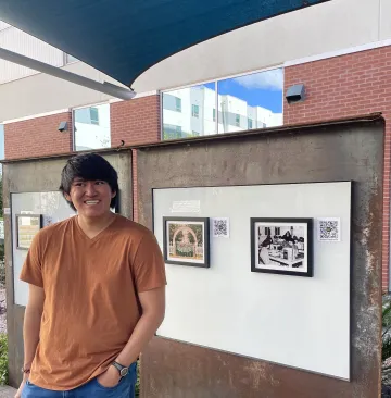 student standing in front of photographs on whiteboard