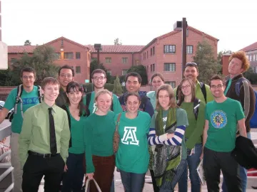 group of people wearing green shirts in front of brick building