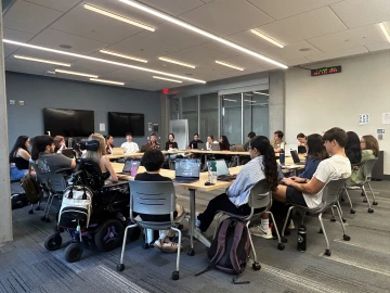 group of students sitting in a group with laptops having discussion