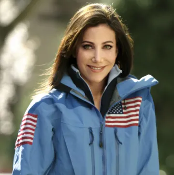 Headshot of Alison Levine - Brunette woman wearing explorer jacket with American flags