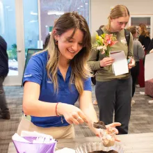 A student putting toppings on her treat during a monthly event.