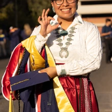 Student at graduation giving the Wildcat sign.