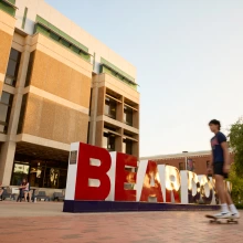 Student walking  in front of main library.