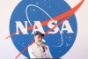dante lauretta speaking with microphone in front of NASA sign