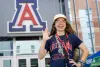 student in front of block A showing wildcat hand gesture