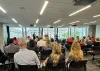 group of people sitting listening to speakers facing away from camera