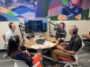 four people sitting in front of podcast mics and equipment speaking to each other